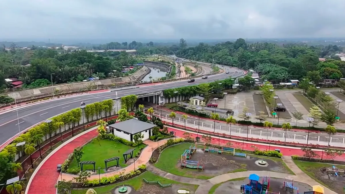 Aerial view of a Davao Coastal Road interchange with a landscaped pocket park and children's playground inside the loop