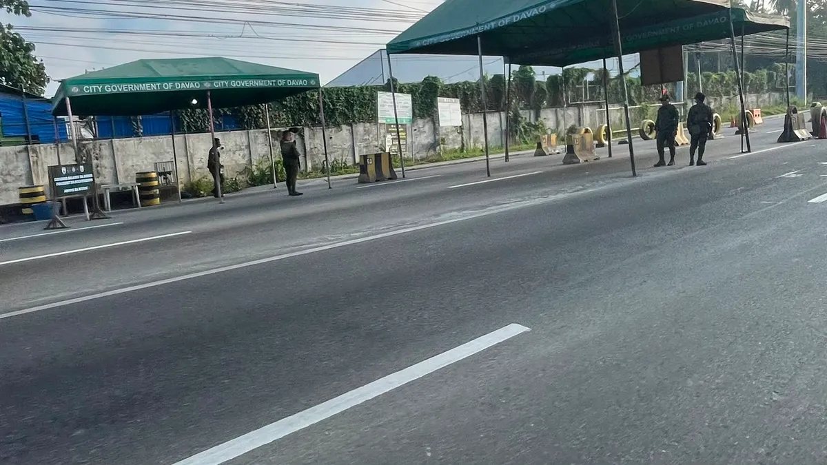 City government tents at a roadside checkpoint with palms behind