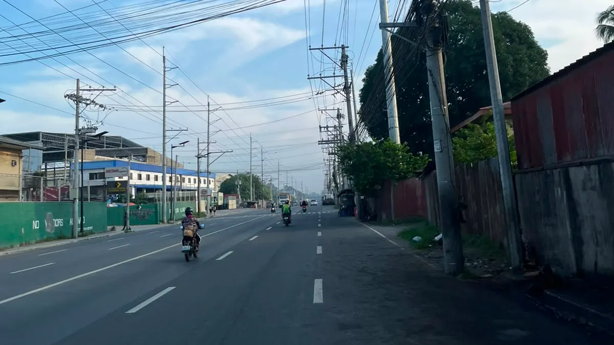 Motorcycle on a road under a dense fan of overhead utility wires